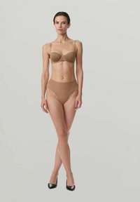 Nude-BH und hoch taillierter Slip aus glattem Stoff, mit dünnen Trägern und nahtlosem Design für Komfort. Model trägt schwarze High Heels.