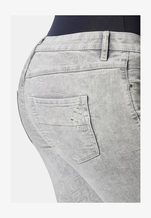 Gray denim jeans feature a fitted design with a back pocket adorned with decorative studs and a subtle faded texture.