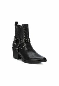 Botas de cuero negras hasta el tobillo con punta afilada, que cuentan con tachuelas plateadas, una correa con hebilla y un diseño de parte superior texturizado. Tacón grueso.