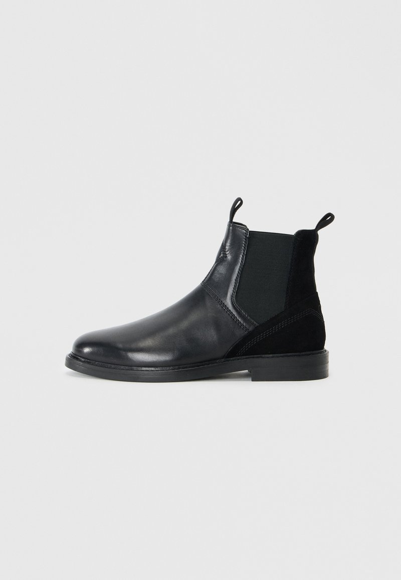 Black chelsea boots featuring smooth leather and suede accents, elastic side panels, rounded toe, and pull tabs for easy wear.