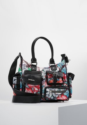Bolso con estampado floral colorido y múltiples bolsillos de cuero negro, asas y una correa de hombro ajustable sobre una superficie blanca.