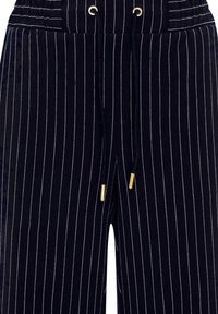Schwarze Nadelstreifen-Hosen mit einem Kordelzugbund, ausgestattet mit goldfarbenen Aglets und einer strukturierten Stoffoberfläche.