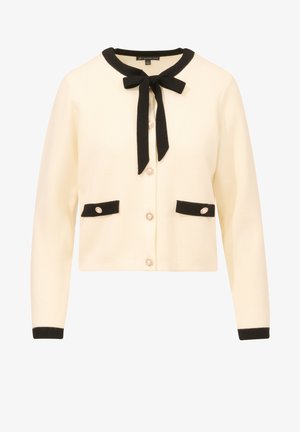 Crème kleurig vest met zwarte bies, heeft een strik bij de hals, twee voorzakken en decoratieve knopen met een parelachtige accenten.