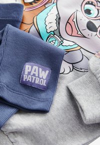 Szary dres z kolorowym nadrukiem postaci z kreskówki, z granatowymi ściągaczami i fioletową metką "PAW PATROL".