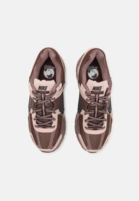 Nike Vomero 5 tenisice s gornjim dijelom od smešnog i ružičastog mrežastog materijala, crnim naglascima, teksturiranim đonovima i kontrastnim vezicama za sigurnije prianjanje.