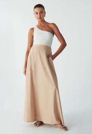 Cap sleeve, ribbed white top with a one-shoulder design paired with a high-waisted, beige flowy maxi skirt featuring side pockets.