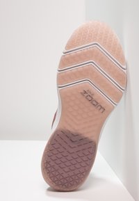 Nike Zoom shoe sole in pink and white, featuring a textured grip pattern with zigzag lines and a visible logo on the side.