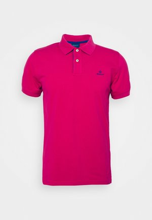 Polo à manches courtes rose vif avec col, deux boutons blancs, et petit logo bleu sur la poitrine gauche.