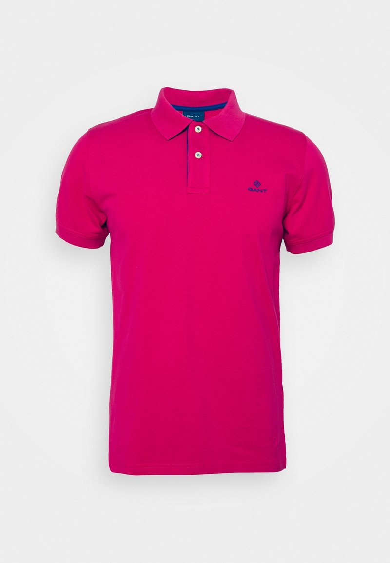 Polo à manches courtes rose vif avec col, deux boutons blancs, et petit logo bleu sur la poitrine gauche.