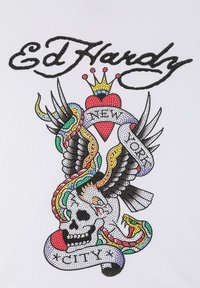 Grafisk t-shirt med en färgglad tatueringsdesign med ett skalle, en örn och ett hjärta. Designen är tryckt på ett vitt tyg.