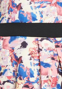 Tissu à motif floral avec des couleurs bleu, rose et crème. Ceinture noire. Le design plissé ajoute de la texture et un intérêt visuel.