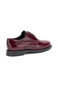 Scarpa stringata in pelle bordeaux con punta arrotondata, texture liscia e suola in gomma nera. Presenta cuciture sottili e un design classico.