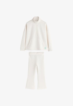 Ensemble deux pièces couleur crème avec un pull à manches longues et demi-fermeture éclair et un pantalon à jambes larges, conçu en tissu doux et confortable.