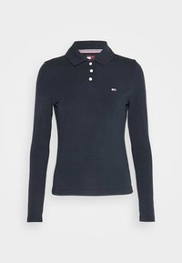 Schwarzes Langarm-Polohemd mit drei weißen Knöpfen und kleinem rechteckigen Logo auf der linken Brust.