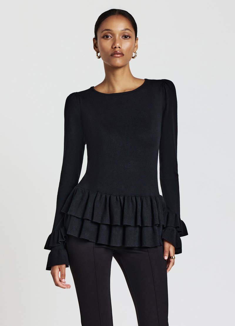 Top nero a maniche lunghe con scollo tondo, tessuto testurizzato e orlo a strati con volant svasati. Silhouette aderente.