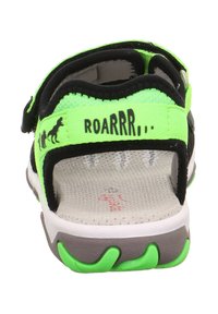 Schwarze Sandale mit neon-grünen Akzenten und verstellbaren Riemen, ausgestattet mit einer strukturierten Sohle und einem "ROARRRR..."-Druck auf der Rückseite.