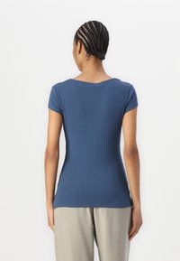 Hladký, krátký rukáv tričko v tmavě modré barvě, se širokým výstřihem a přiléhavým siluetou, spárované s světle šedými kalhotami.