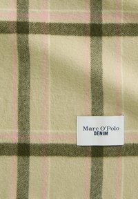 Tkanina mieszana z wełną o wzorze w kratę w stonowanych kolorach zieleni, różu i beżu. Posiada białą metkę z napisem "Marc O'Polo DENIM" w ciemnym kolorze.