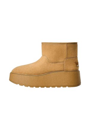 Tan suède enkellaars met een ronde neus en een dikke platformzool. Gedetailleerde stiksels langs de naden en een logo-accent op de hak.