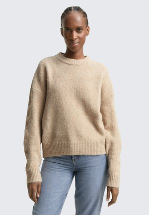 Pull en tricot beige avec une finition texturée, des poignets côtelés et un col rond. Assorti à un jean en denim bleu clair. Design simple et décontracté.