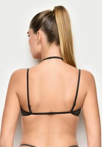 Top bikini nero con sottili spalline regolabili, design in rete testurizzata e chiusura con gancio sul retro. Stile a copertura minima.