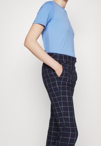 Ljusblå kortärmad t-shirt i kombination med marint rutiga byxor, med ett rutmönster i ljusblått och vitt, med sidfickor.
