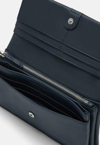 Granatowy skórzany portfel z zamkiem błyskawicznym, wieloma przegródkami na karty oraz zatrzaskiem. Teksturowane wykończenie z detalem w postaci srebrnej okucia.