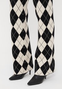 Zwart en crèmekleurige argyle-patroon wijde broek gecombineerd met puntige zwarte hakken met een gladde afwerking en een lage stilettohak.