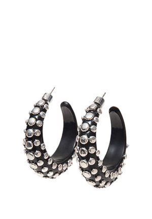 Čierne náušnice v tvare polmesiaca s vystupujúcimi striebornými kruhovými cvokmi pokrývajúcimi vonkajší povrch a kovovými zátkami na zadnej strane.