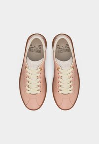 Ζεύγος ροζ δερμάτινα αθλητικά με κορδόνια, με εκρού κορδόνια και καφέ λαστιχένιες σόλες, σε προβολή από πάνω σε λευκό φόντο.