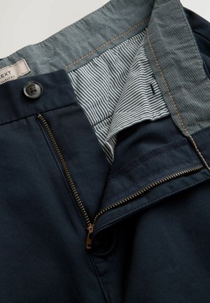 Marineblaue, gerade geschnittene Hose mit Reißverschluss und Knopfverschluss sowie gestreifter Stoffauskleidung am Bund. Sichtbare Nähte.