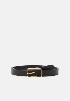 Ceinture en cuir noire avec une petite boucle rectangulaire dorée, enroulée à plat sur un fond gris clair.