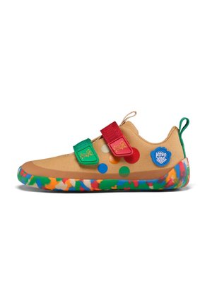 Baskets beige pour enfant avec des pois colorés, des bandes velcro rouges et vertes, un écusson logo bleu et une semelle multicolore tachetée.