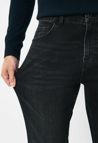 Mustad denim teksad, millel on kerge venivus, klassikalise viie tasku kujundusega ja nööpkinnis. Kanga pinnal on peen tekstuur ja sära.