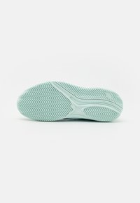 Sola de sapato atlético azul claro com um padrão de área de herringbone, apresentando sulcos flexíveis e uma superfície texturizada para tração.