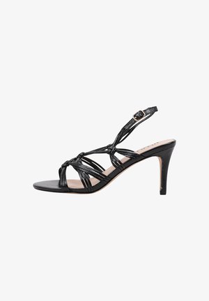 Sándal de tacón alto de cuero negro con un diseño de tiras, acentos anudados y correa de tobillo ajustable. Textura suave y silueta elegante.
