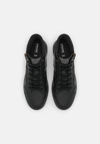 Baskets en cuir noir avec lacets et fermetures éclair latérales, semelles intérieures de marque, vues de dessus sur un fond clair.