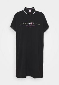 Černé polo šaty Tommy Jeans s krátkými rukávy, bílým lemem na límci a rukávech a logem "Tommy Jeans New York City" na hrudi.