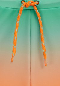Grønne og orange badebukser med en gradient-effekt. Har en flettet orange snor med turkise detaljer og metal aglets.