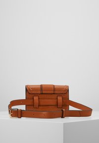 Ruskea nahkabag, jossa on teksturoitu krokotiilikuosi, suorakaiteen muotoinen, säädettävä olkahihna ja läppä sulkeminen, jossa on keskeinen yksityiskohta.