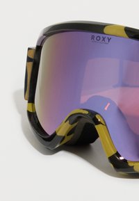 Laskettelulasit mustakeltaisella maastokuvioisella kehyksellä, violetti peililinssi ja musta vaahtomuovipehmuste mukavuutta varten. Roxy-brändäys näkyvissä.