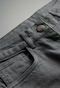 Hallid hallid denim püksid, mis omavad eesnupu sulgemist, vöökohaga silmadega ja kül pockets, millel on nähtav õmbluse detail.