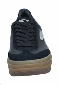 Chaussure de sport noire avec tige en daim et cuir, lacets texturés, et une épaisse semelle en caoutchouc translucide. Présente un petit logo sur le côté.