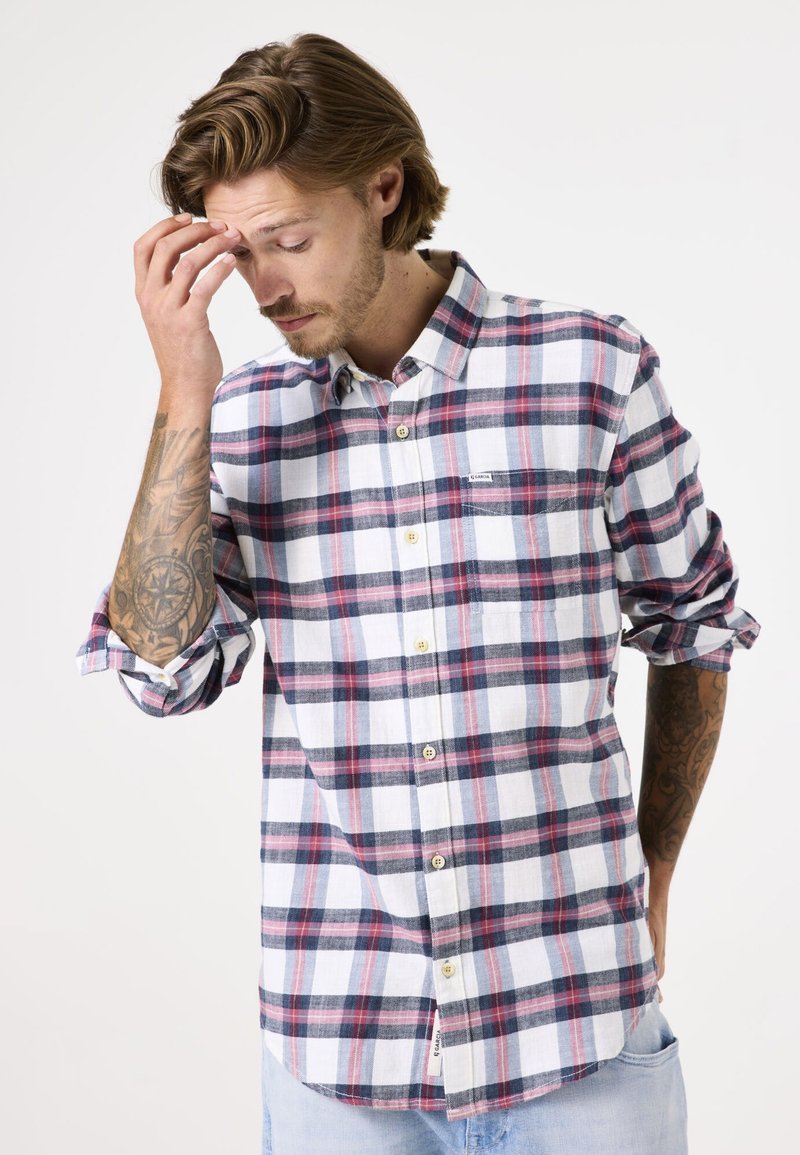 Geruite button-up shirt in wit, rood en marineblauw. Lange mouwen met opgerolde manchetten, één borstzak en een ronde onderkant. Katoenen stof.