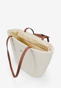 Bolso tote de tejido beige con asas de cuero marrón y cierre de botón a presión. Interior de tela de color claro con un bolsillo deslizante para organización.