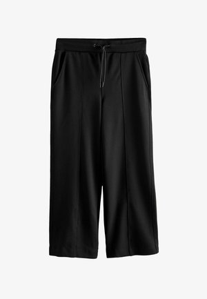 Pantalons larges noirs en tissu lisse, présentant une taille élastique avec cordon de serrage et deux poches devant.