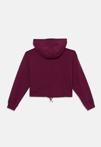 Moleton cropped em bordeaux com cordão na barra, mangas longas e capuz. Tecido liso com um design minimalista.