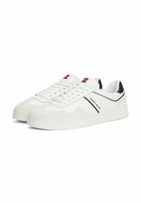 Zapatillas blancas de cuero y ante, con un acento negro, cordones planos y un logo en la lengüeta. Diseño clásico de caña baja.