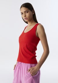 Czerwony prążkowany top na ramiączkach z okrągłym dekoltem, w połączeniu z luźnymi, jasnoróżowymi szortami z bocznymi kieszeniami. Gładka tekstura i casualowy fason.