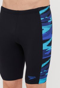 Short de bain Speedo en noir avec des motifs abstraits bleus sur le côté, fabriqué en matériau extensible, présentant un design ajusté et un détail de logo.